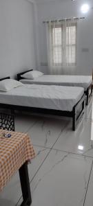 two beds sitting in a room with a table at Pynadath Square in Adūr +3 photos
