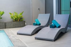 - un groupe de trois chaises assises à côté d'une piscine dans l'établissement Nicky Luxury Private Pool Villa in BangTao Laguna, à Laguna Phuket