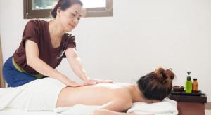 a woman sitting on a bed with a woman touching a stomach at The One Residence Hotel in Bangkok