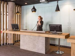 a woman talking on a phone at a reception desk at ibis Lille Centre Grand Palais in Lille