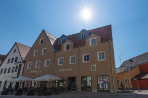 a building in a town with the sun behind it at Hotel im Ried in Donauwörth