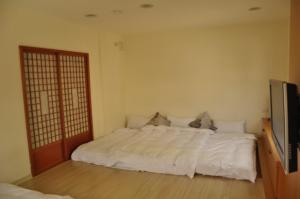 a bedroom with a white bed and a tv at LK Breakfast and Beds in Lukang