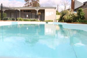 a swimming pool with a pool table and chairs at Hermitage Motel in Muswellbrook