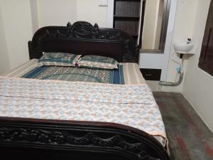 a bed with a black frame and pillows on it at Sai Swastik Homestay Hampi in Munirābād