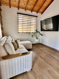 a living room with a white couch and a tv at Magnífica Cabaña en Pony Parque Mesa de los Santos in Piedecuesta