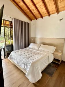 a bedroom with a large bed with white sheets at Magnífica Cabaña en Pony Parque Mesa de los Santos in Piedecuesta