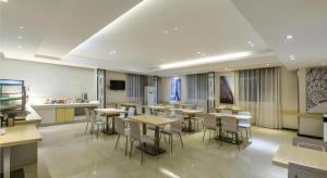 une salle de classe avec des tables et des chaises dans une cafétéria dans l'établissement City Comfort Inn Hotel Guiyang Normal University Yangmingci Metro Station, à Guiyang