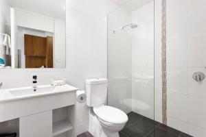 a white bathroom with a toilet and a shower at Bayside Geelong Hotel & Apartments, an Ascend Collection Hotel in Geelong