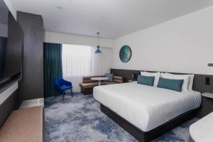 a hotel room with a large bed and a chair at Bayside Geelong Hotel & Apartments, an Ascend Collection Hotel in Geelong