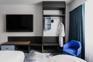 a bedroom with a bed and a tv and a blue chair at Bayside Geelong Hotel & Apartments, an Ascend Collection Hotel in Geelong