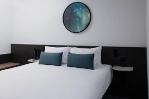 a bedroom with a large bed with a clock on the wall at Bayside Geelong Hotel & Apartments, an Ascend Collection Hotel in Geelong