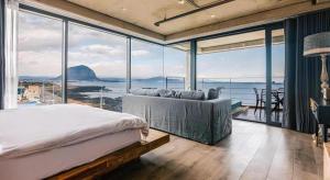 a bedroom with a bed and large glass windows at Tropical Hideaway in Seogwipo