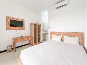 努沙杜瓦Kanha Homestay near Pantai Pandawa RedPartner的一间卧室，墙上有一张床和一台电视