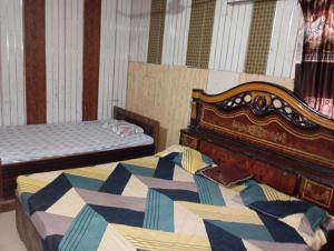 a bedroom with two beds and a wooden headboard at Kaushalya Devi Dharamshala in Mathura