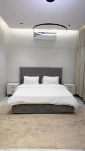 a bedroom with a large white bed and a chandelier at Luxury 2BR Apartment -Prime Area in Jeddah