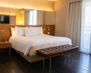 a hotel room with a large bed and a bench at Radisson Blu São Paulo in Sao Paulo