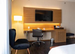 a hotel room with a desk with a television and chairs at Radisson Blu São Paulo in São Paulo