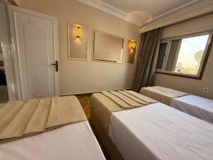 Una habitación de hotel con tres camas y una ventana. en Grand Royal central Cairo Home, en El Cairo