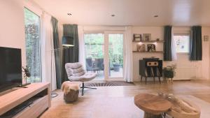 a living room with a tv and a chair and a table at Vliegend Hert, Direct in de Natuur op de Veluwe in Emst