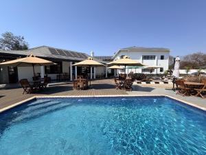 a swimming pool with tables and chairs and umbrellas at 10 on Pauling Hotel Bulawayo in Bulawayo
