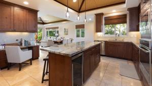 a large kitchen with wooden cabinets and a large island at HAWAIIAN DREAM Relaxing KaMilo 3BR Home with Private Beach Club in Waikoloa