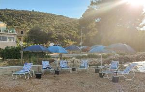 Un grupo de sillas y sombrillas en una playa. en Amazing Apartment In Janjina With Lake View, en Drače