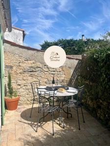 una mesa con sillas y una botella de vino en el patio en L'Instant Terrière - Quartier Calme - Proche plage, en La Tranche-sur-Mer