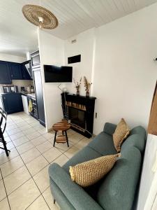 sala de estar con sofá verde y chimenea en L'Instant Terrière - Quartier Calme - Proche plage, en La Tranche-sur-Mer