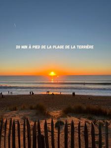 puesta de sol en una playa con una valla de madera en L'Instant Terrière - Quartier Calme - Proche plage, en La Tranche-sur-Mer