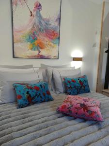 a bed with two pillows and a painting on the wall at Ioni Home in Tsagarada