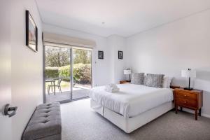 a white bedroom with a bed and a sliding glass door at XYZ Holiday Home in Quindalup