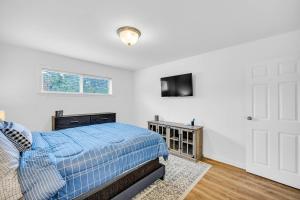 a bedroom with a blue bed and a television at Classic City Getaway - Walk to Sanford Stadium in Athens +16 photos