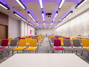 une pièce vide avec des chaises, des tables et des lumières violettes dans l'établissement Mercure Krakow Stare Miasto, à Cracovie