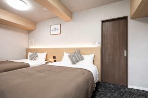 a hotel room with two beds and a door at b&難波1号店 in Osaka