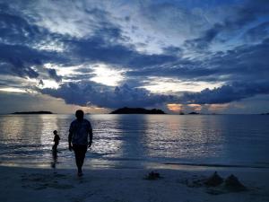 a man and a child walking on the beach at Hotel Purnama Lenggang in Gantung