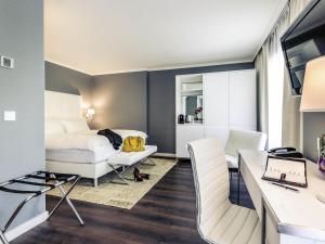 a bedroom with a bed and a desk and chairs at Mercure Hotel Raphael Wien in Vienna +60 photos