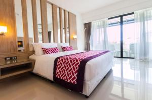 a bedroom with a large bed with red and white pillows at The Par Phuket Hotel in Ban Thung Thong