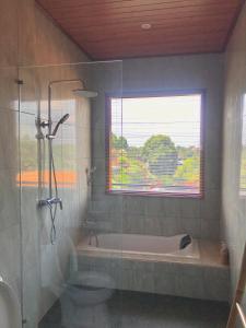 a bathroom with a shower and a tub and a window at Heri house ubud in Ubud