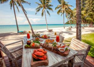 une table avec de la nourriture sur la plage avec des palmiers dans l'établissement Wendy the Pool Resort @ Koh Kood, à Ko Kood