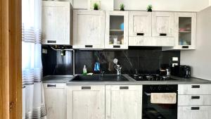 a kitchen with white cabinets and a sink at Trilocale con giardino, posto auto e wi-fi - P034 in Porto Recanati +6 photos