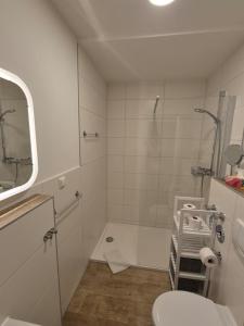 a white bathroom with a shower and a toilet at Strandstudio 19, Exklusive Wohnung, erste Reihe, Strand, Kamin in Binz +29 photos