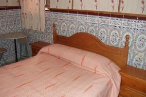 a bed in a bedroom with a white bedspread at Hostal Alcázar in Córdoba