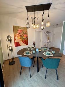 a dining room with a table and blue chairs at Klinik & Kurpark Parkplatz Barrierefreies Apartment Boxspringbett in Bad Oeynhausen +10 photos