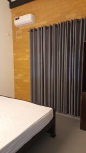 a room with two beds and a window with grey curtains at The Belle Denipitiya in Welihinda