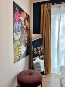 a room with a purple stool and a painting on the wall at Klinik & Kurpark Parkplatz Barrierefreies Apartment Boxspringbett in Bad Oeynhausen