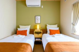 two beds in a small room with orange pillows at Tokinoma Furano in Furano +165 photos