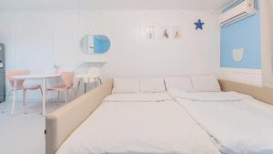 a white room with two beds and a table at Taean Lily Pension in Taean +12 photos