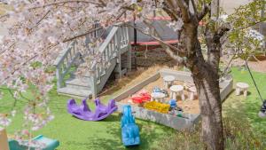 a toy playground in a yard with a tree at Taean Lily Pension in Taean