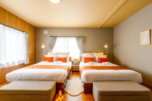 three beds in a room with a window at Tokinoma Furano in Furano
