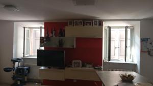 Pokój z 2 oknami i biurkiem z telewizorem w obiekcie Vezzano Home w mieście Vezzano